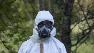 Man in bio hazard wuit and gas mask