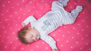 cute infant sleeping on a blanket happy with paci in mouth