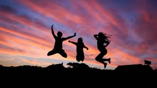 three people jumping up in the sun set happy