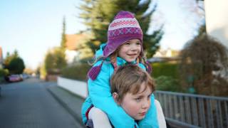 little sister riding on her borthers shoulders happy dressed warm