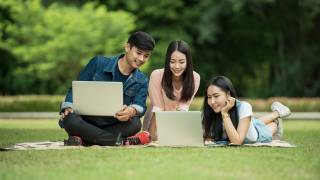 young adults studying on lawn