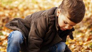 young boy playing in fallen leaves